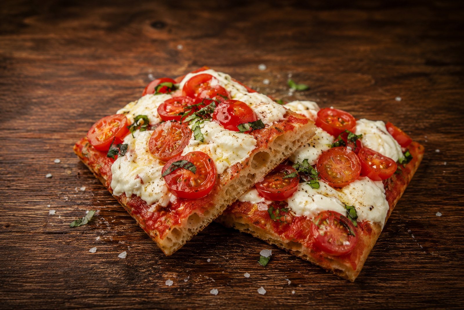 Deux morceaux de pizza Margherita : stracciatella, tomates cerises et basilic